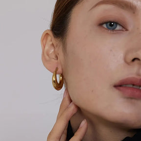 Foto frontal de uma Mulher usando o Brinco Feminino Argola Dourada Larga Meia Lua Selene - Banhado a Ouro 18k