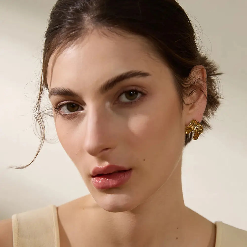Brinco Feminino Dourado ondulado com design irregular e brilho delicado, modelo usando