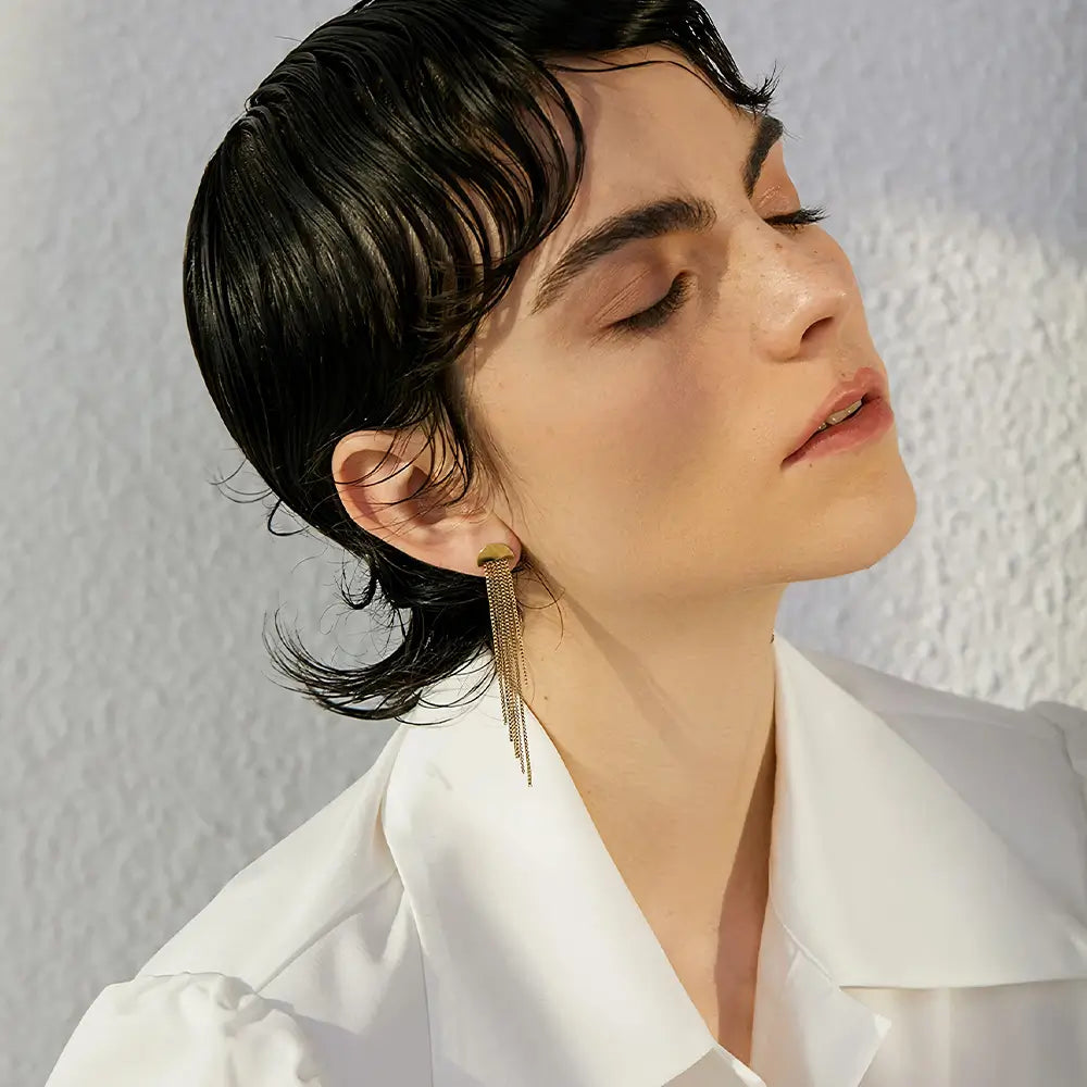 Brinco Feminino Dourado pendente com pingente de borla e brilho elegante, mulher usando