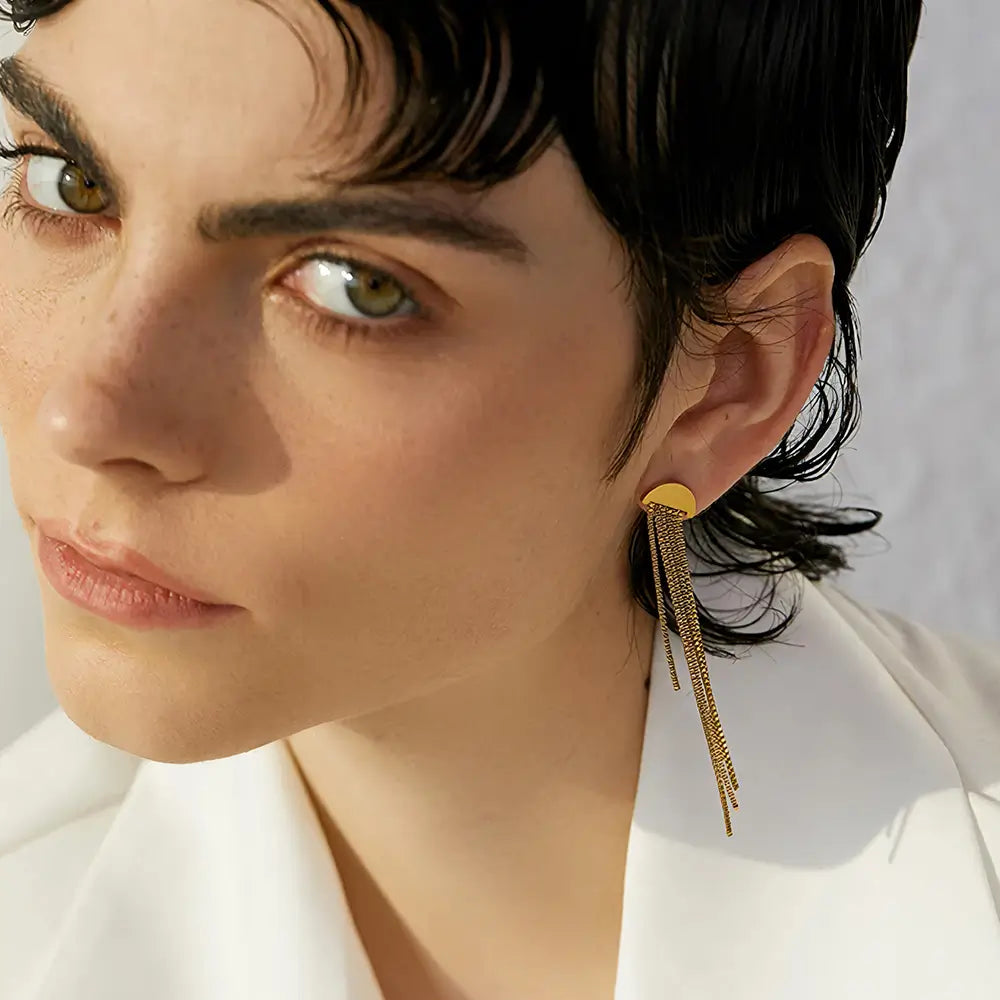 Brinco Feminino Dourado pendente com brilho dourado e design fluido, modelo utilizando