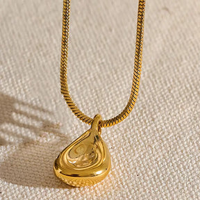 Colar Feminino Dourado corrente rabo de rato com pingente abstrato Luriane em fundo neutro e iluminação suave