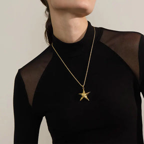 Mulher usando o Colar Feminino Dourado Longo Cordão Baiano com Pingente Estrela do Mar Marella - Banhado a Ouro 18k