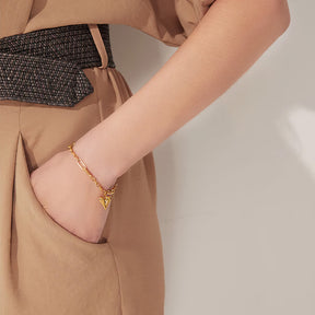 Mulher elegante usando a Pulseira Dourada Feminina de Elos com Pingente de Coração Eloria – Banhada a Ouro 18k
